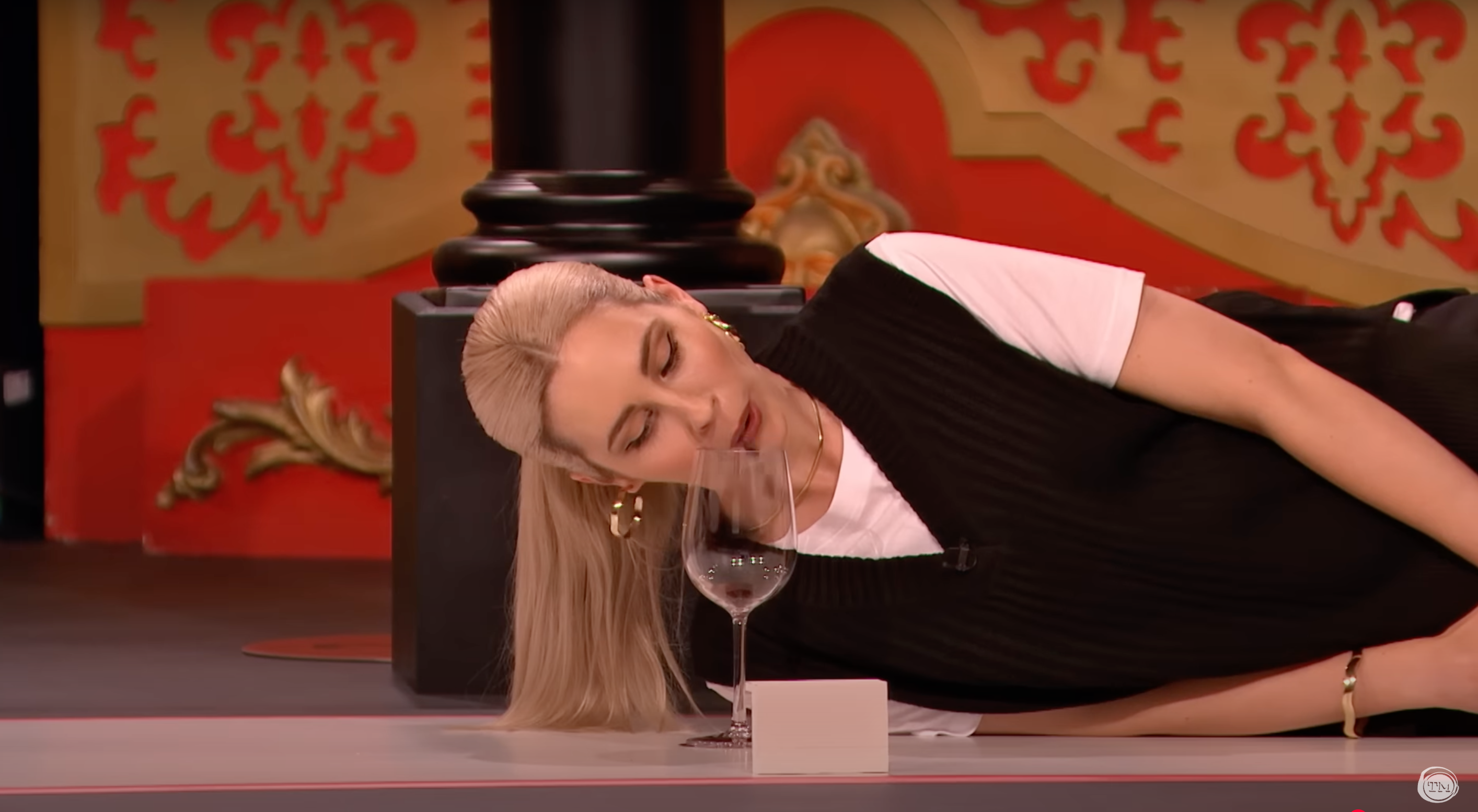 Stevie Martin lying on her side, spitting raisins into a wine glass.